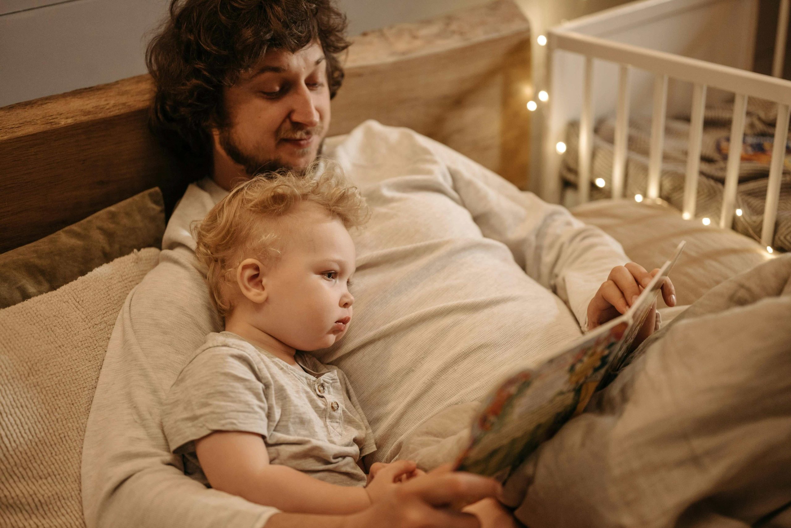 A father and young child reading a book together in bed, symbolising shared parenting responsibilities in Australia.